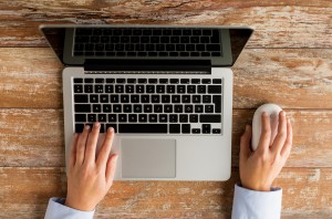 business, education, people and technology concept - close up of female hands with laptop and computer mouse on table